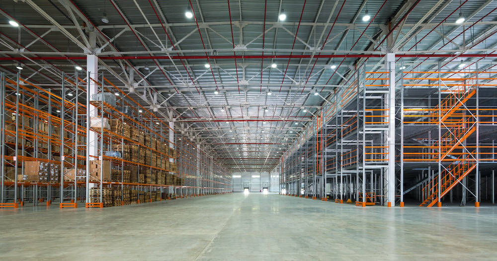 A sprawling warehouse, mostly empty but with lots of shelves.