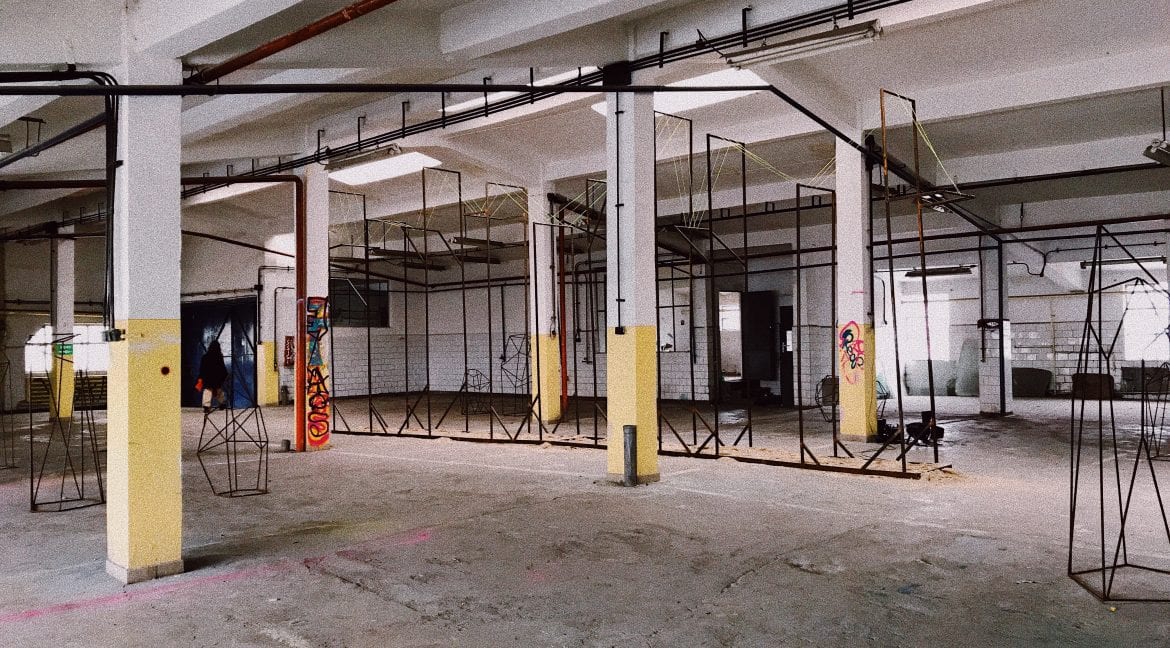 A large, empty warehouse with high ceilings held up by large white and yellow pillars.